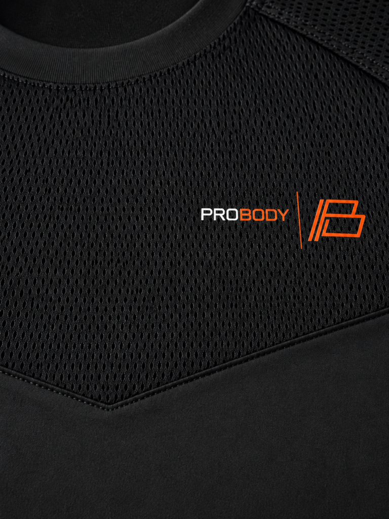 Close-up of the black ProBody performance tee chest showing the mesh chevron panel and the orange PROBODY B-mark