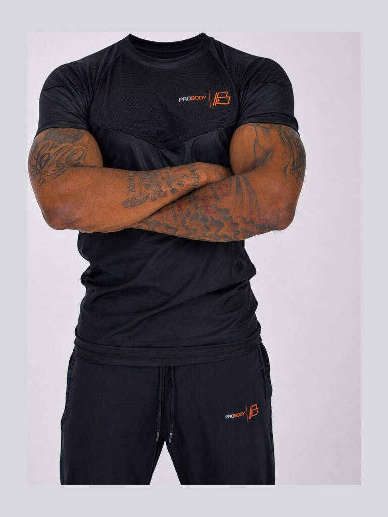 Man wearing the black ProBody performance tee with his arms folded, showing the mesh chevron panel across the chest